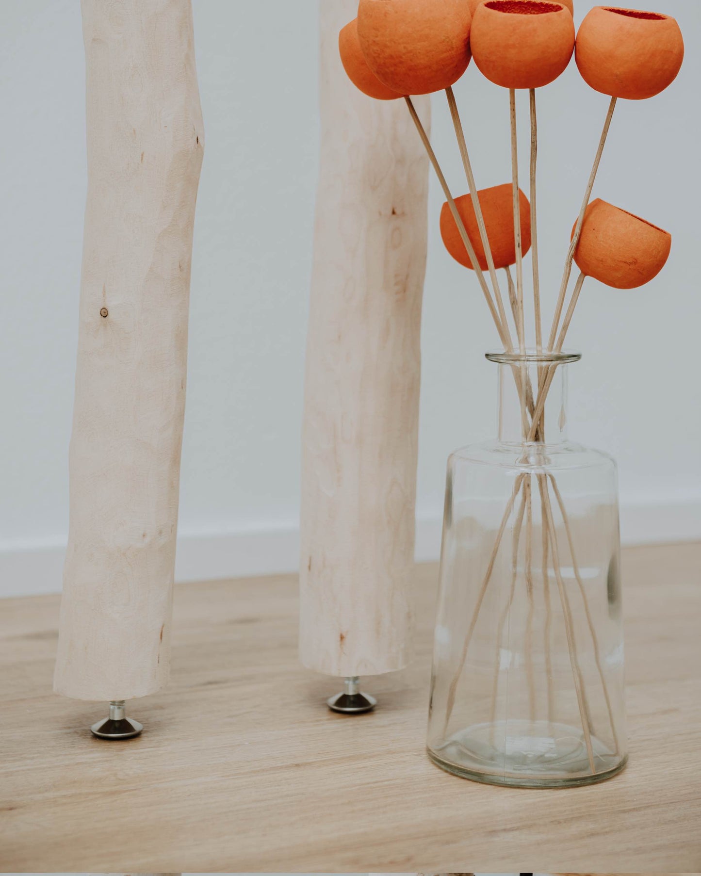 Entrindeter Birkenstamm mit Stellfuß und Dekorationsblumen mit Vase im Vordergrund zu sehen. Dekowald ist der Anbieter dieser Artikel.