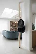 Gardrobe aus Birke an einer Wand mit Couch im Hintergrund. Es sind auch Regale mit Bücher zu sehen.