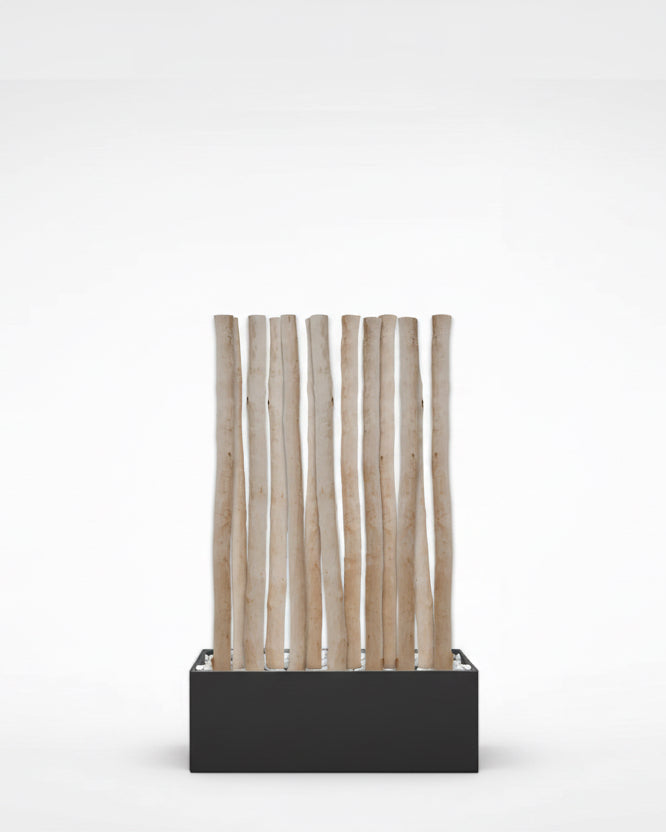 Natürlicher Raumtrenner aus entrindeten Birkenstämmen in einem rechteckigen Kasten mit Kiesfüllung
